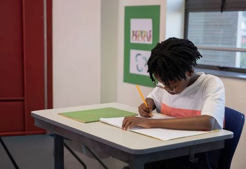 African american student writing at desk concentrating on classroom work and study