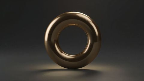 Polished bronze torus ring reflecting soft spotlight on dark matte floor