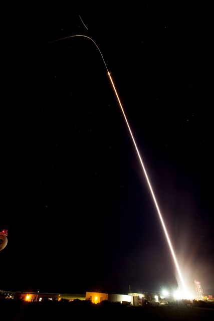 The image captures the late-night launch of NASA's Terrier-Improved Malemute sounding rocket from the Wallops Flight Facility in Virginia. The long exposure of the photo shows a bright trail as the rocket ascends into the night sky. This rocket event was unique as it released 10 canisters, deploying colorful blue-green and red vapor traces to form artificial clouds visible from New York to North Carolina, aiding scientific studies on the ionosphere and auroras. Suitable for educational content, science communication, aerospace technology promotion, and space-themed publications.