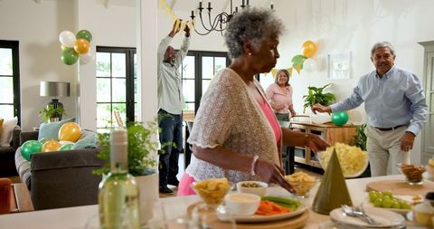 Seniors Joyfully Preparing Birthday Celebration in Living Room