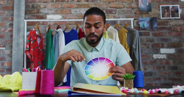 Biracial male fashion designer showing colours pallet looking at camera and smiling - Download Free Stock Photos Pikwizard.com