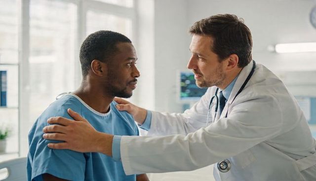 Physician comforting black patient during clinic consultation showing empathy and trust