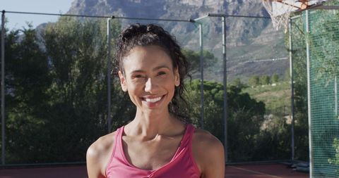 Smiling Female Basketball Player on Outdoor Court on Sunny Day