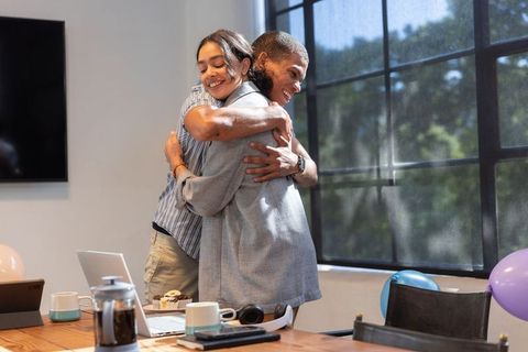 Cheerful Colleagues Hugging Celebrating Success in Modern Office