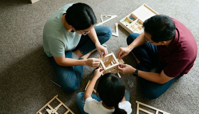 Family building wooden model house together on carpet diy crafting teamwork parenting kids