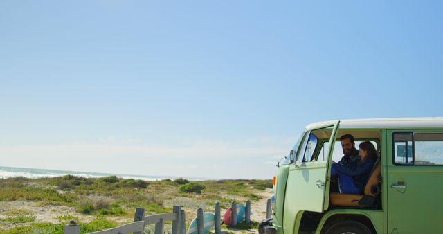 Couple sitting in a retro van at the beach, enjoying the ocean view. Ideal for themes of travel, adventure, romance, summer holidays, and camping. Perfect for blogs, magazines, travel agencies, and advertisements promoting road trips and beach vacations.