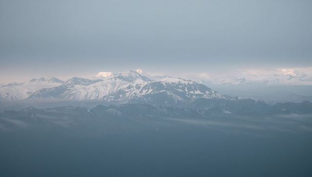 Misty snow-capped mountain panorama featuring distant glaciers and layered alpine ridges