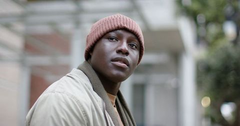 African American Young Man Gazing Upward Under Urban Canopy Wearing Beanie and Scarf