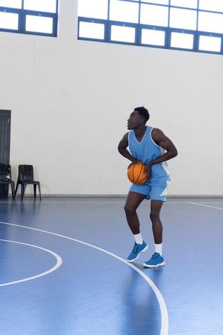Basketball Player Holding Ball on Blue Indoor Court
