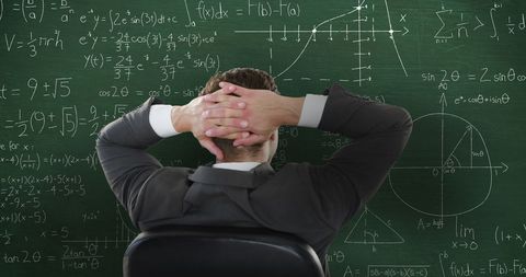 Pensive Man Looking at Complex Mathematical Formulas on Chalkboard