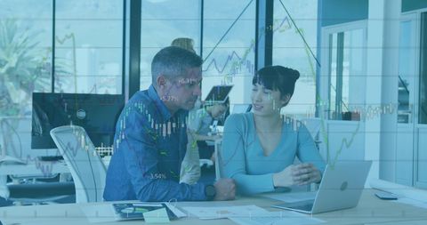 Colleagues analyzing financial trends on digital graphs in modern office
