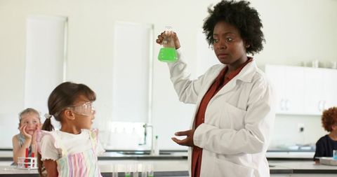 African american teacher demonstrating colorful chemistry experiment to elementary students