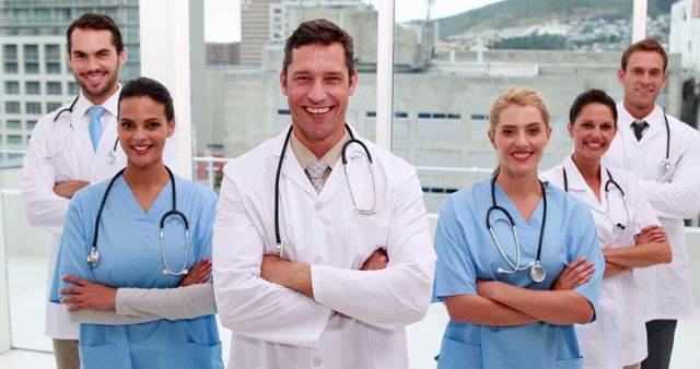 Medical team of doctors and nurses standing confidently with arms crossed, smiling and looking at the camera. Professionals wear stethoscopes and uniforms, showcasing a sense of teamwork and expertise. Ideal for use in healthcare promotional materials, hospital websites, brochures, and advertisements highlighting professionalism and patient care.