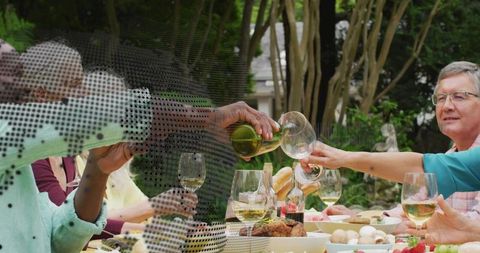 Multigenerational Family Toasting White Wine at Sunlit Backyard Dinner Party