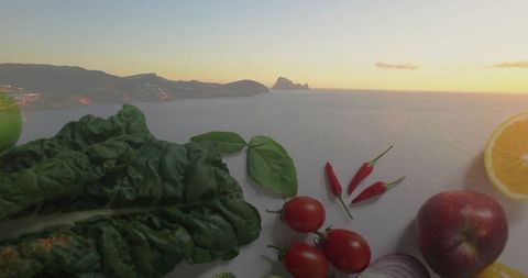 Fresh produce displayed on white terrace overlooking coastal scenery