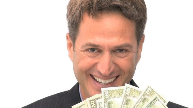 A businessman with short dark hair smiling excitedly while holding several dollar bills. The video focuses on his joyful expression and the money in his hand, suggesting themes of financial success, wealth, and prosperity. This video is ideal for marketing materials related to finance, banking, investment, business success stories, and promotions highlighting economic growth or profitability.