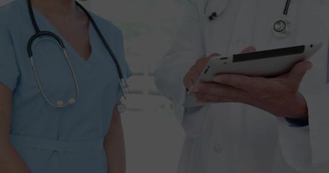 Medical Team Consulting on Tablet in Clinic Reviewing Digital Patient Records and Charts