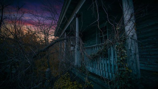 Eerie abandoned rustic porch at dusk with overgrown vines and weathered paint