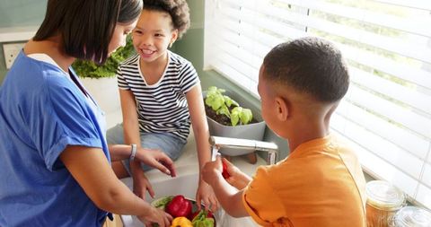 Family Washing Fresh Vegetables Together in Sunny Kitchen