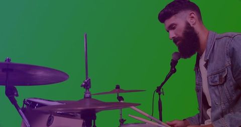 Bearded musician drumming and singing against green screen