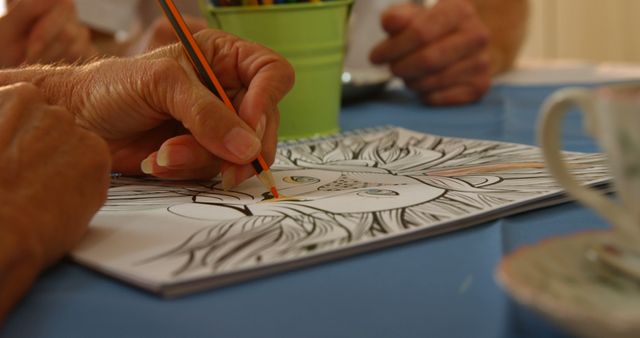 Senior adult engaging in coloring intricate mandala design book. Image is perfect for use in articles or materials about adult coloring books, art therapy, senior hobbies, stress-relief activities, and creative pastimes for the elderly.