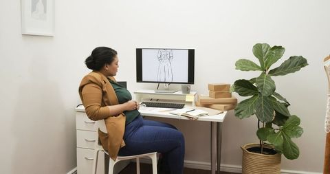 African american fashion designer reviewing dress sketch at minimalist home studio desk