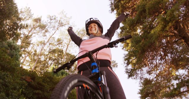 A middle-aged Caucasian woman celebrates a successful bike ride in a forested area, with copy space - Download Free Stock Photos Pikwizard.com