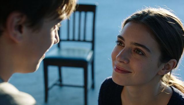 Kneeling woman smiling and looking up at partner, intimate candid moment with wooden chair