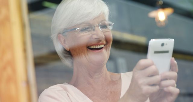 Smiling senior woman using smartphone indoors - Download Free Stock Images Pikwizard.com