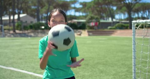 Young african american girl playing soccer on sunlit turf practicing ball control