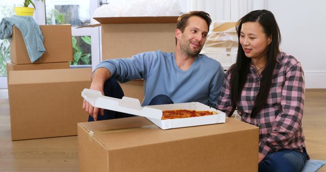 Happy couple eating pizza while moving into new home - Download Free Stock Images Pikwizard.com