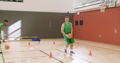 Basketball players dribbling through cone drill on indoor court practicing teamwork