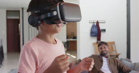 Child Exploring Virtual Reality While Father Watches in Living Room