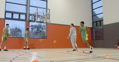 Basketball Coach Leading Training with Diverse Team in Sports Hall