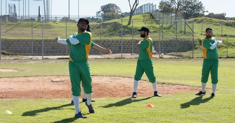 Amateur baseball players stretching on infield during pregame warmup with cones