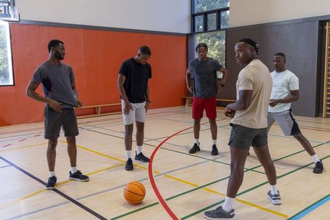 Young african american men gathering around basketball on gym court preparing to play