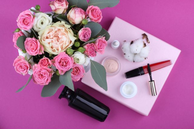 Beauty and skincare products beautifully arranged alongside a vibrant bouquet of pink roses on a pink background. Perfect for blogs and articles about feminine beauty, product advertisements, floral arrangements, or luxurious self-care routines.