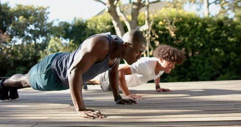 Diverse Friends Exercising with Push-ups in Sunlit Backyard