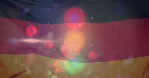 German flag fabric displaying colorful bokeh flares, wrinkled texture and soft glow