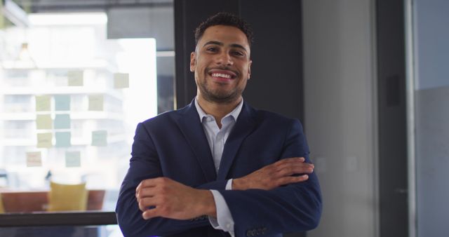 Portrait of biracial businessman with arms crossed smiling looking at camera. work at an independent creative business.