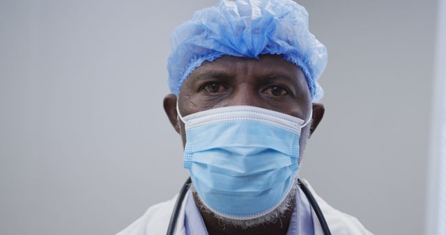 Portrait of african american male doctor wearing face mask and surgical cap. medicine, health and healthcare services during coronavirus covid 19 pandemic.