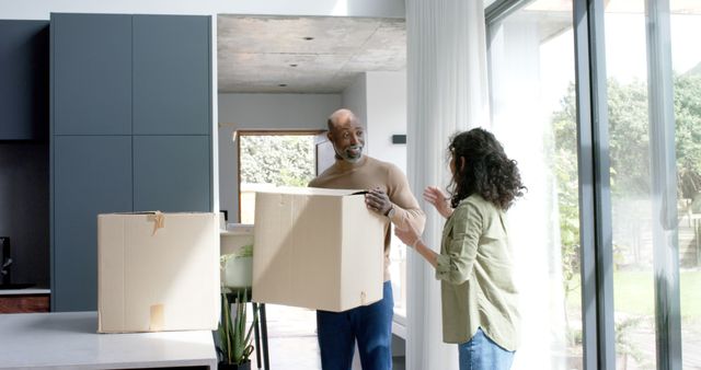 Happy biracial couple talking and carrying cartons at new house - Download Free Stock Photos Pikwizard.com