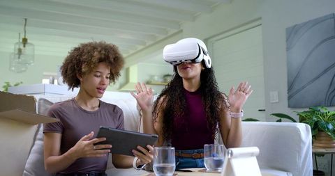 African American friends trying virtual reality headset while unboxing tablet and laughing