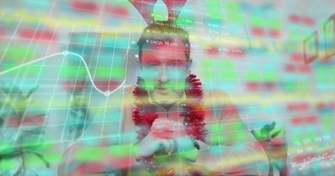 Mature man celebrating at desk wearing tinsel and party hat with financial market overlay