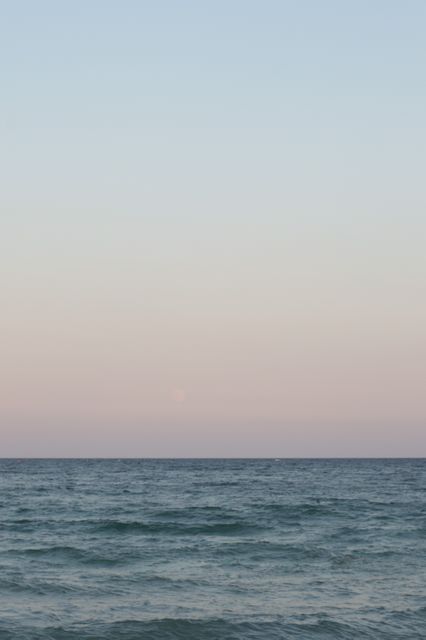 Calm ocean during sunset with a serene horizon and pastel sky. Perfect for use in nature calendars, travel advertisements, relaxation and wellness promotions, and artistic wall prints.