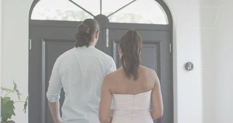 Couple entering foyer through black double doors with arched transom and natural light
