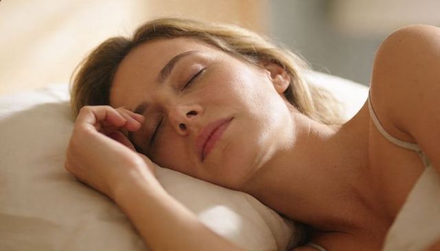 Woman sleeping peacefully on pillow close-up in warm morning light