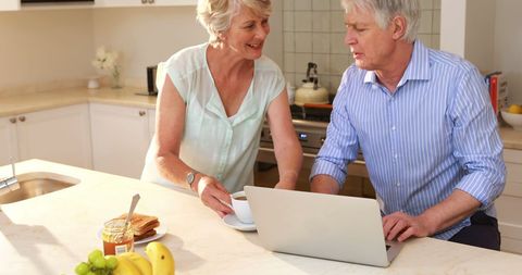 Happy Senior Couple Using Laptop in Sunny Home Kitchen - Download Free Stock Images Pikwizard.com