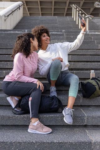 Friends taking selfie on urban stairs wearing activewear and sneakers