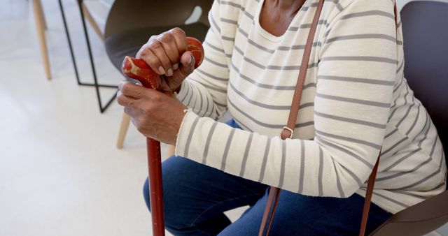 Senior Woman Sitting in Modern Chair Holding Walking Cane - Download Free Stock Images Pikwizard.com